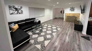 Un salon moderne avec un canapé noir, un tapis à motifs et une cheminée.