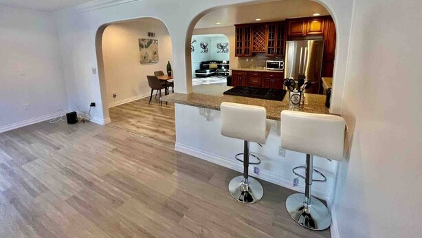 Une cuisine spacieuse équipée d’appareils électroménagers modernes, un coin repas avec une table et des chaises, et un bar avec des tabourets.