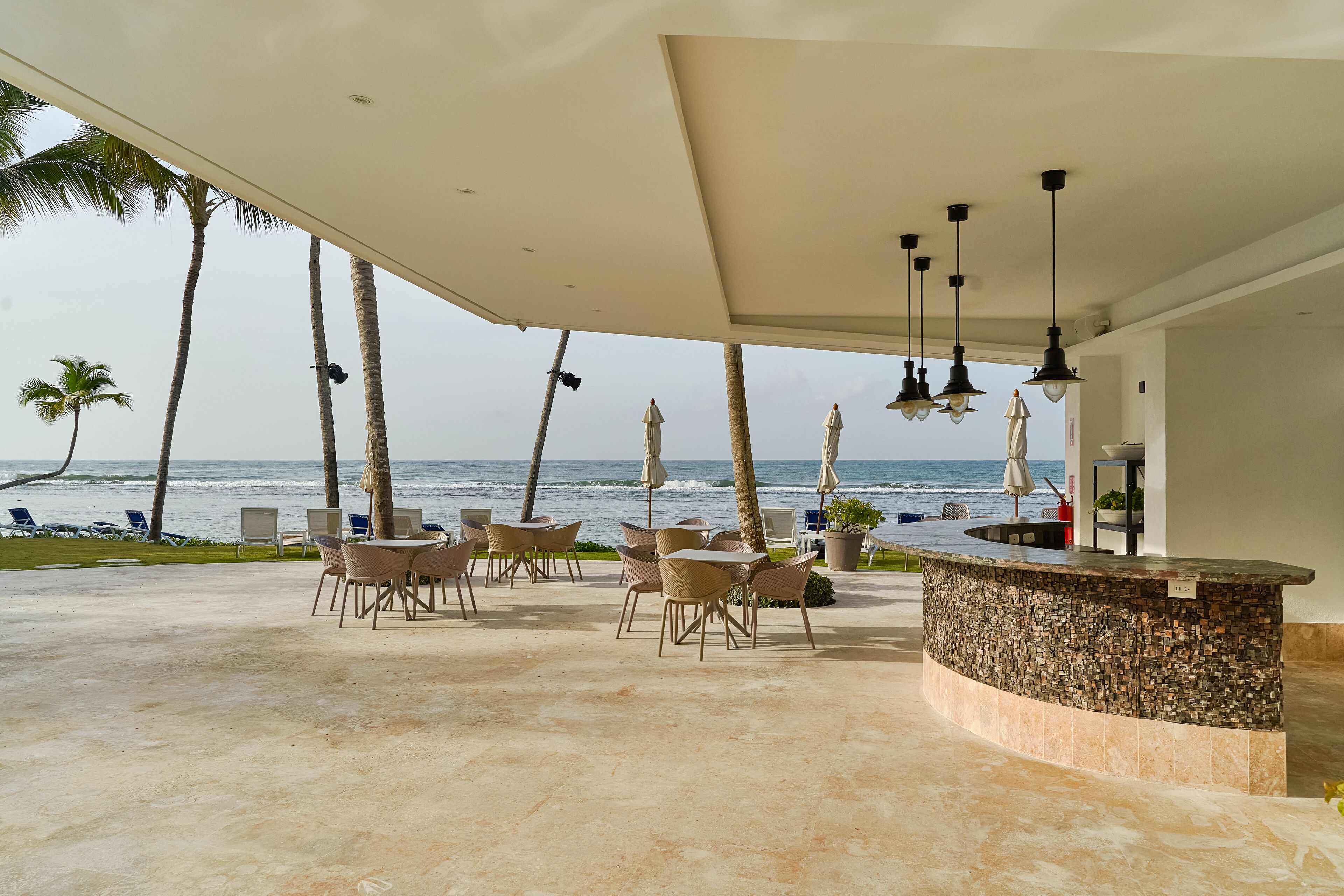 An outdoor seating area with a curved bar, overlooking the ocean.