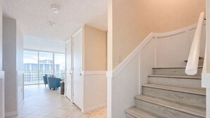 Un apartamento moderno con una escalera, un balcón con una silla azul y vistas a la ciudad.