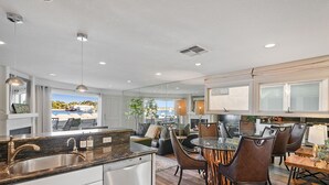 Een moderne keuken met een groot eiland, inbouwapparatuur en een eethoek met een glazen tafel en stoelen.