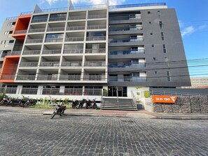 A multi-story building with balconies, a staircase, and a sign indicating 'BOX 150'. - Bela Hospedagem - Lindo flat no Box 150 (João Pessoa)