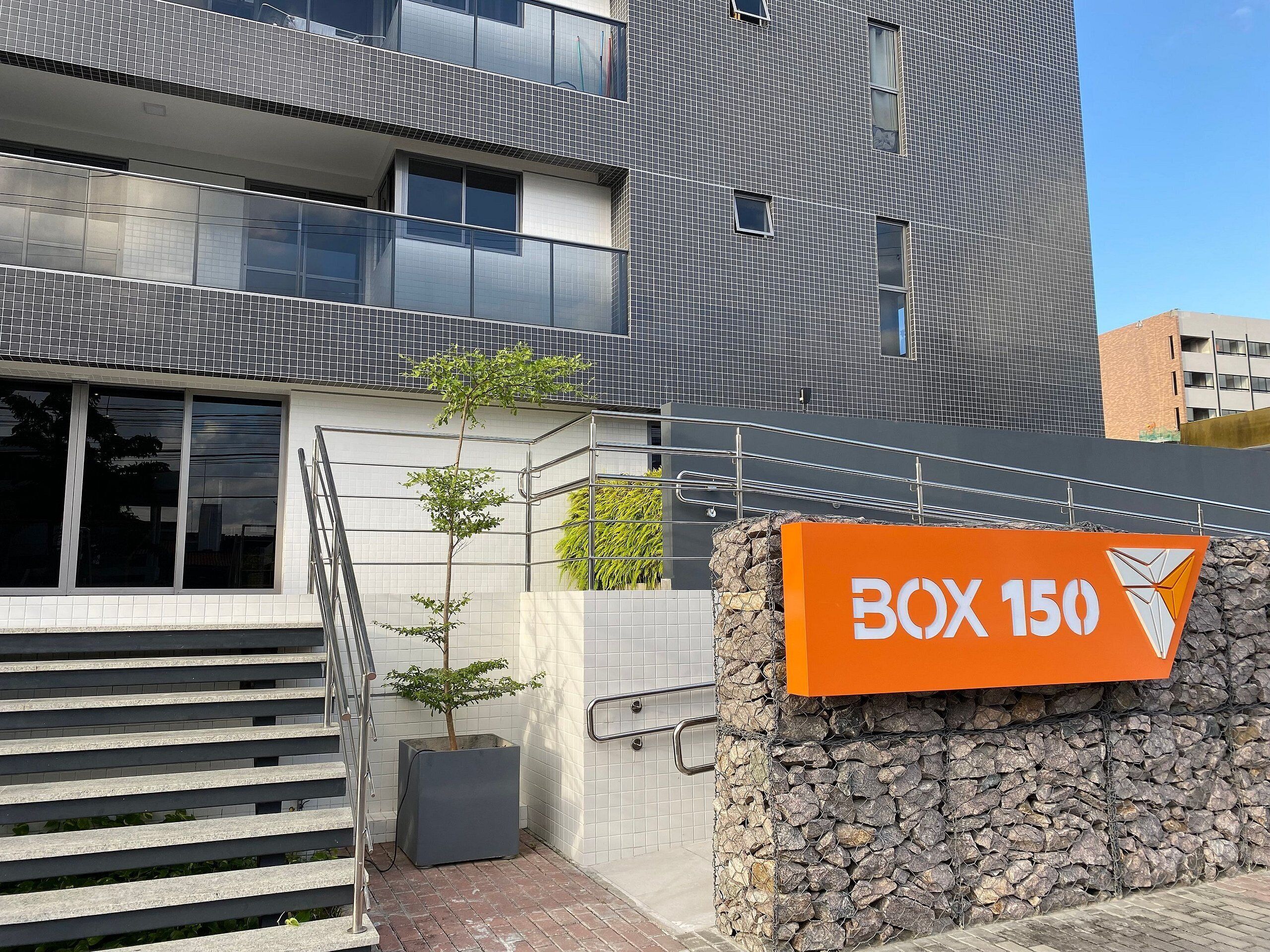 A modern building with a sign reading 'BOX 150' and a staircase leading to an upper level.