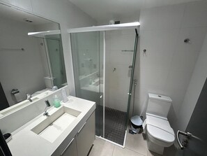 A modern bathroom with a glass-enclosed shower, a white sink, and a toilet. - Bela Hospedagem - Lindo flat no Box 150 (João Pessoa)