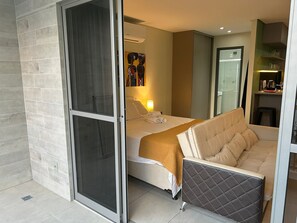 A hotel room with a bed, a sofa, a bathroom, and a kitchenette. - Bela Hospedagem - Lindo flat no Box 150 (João Pessoa)