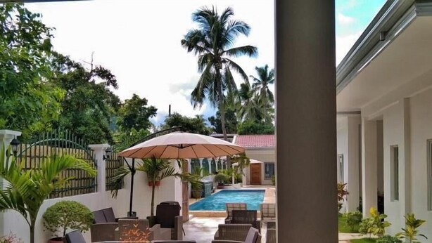 A poolside area with outdoor seating and a view of a swimming pool. - Tequila Cove (Panglao)