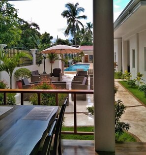 A poolside area with outdoor seating and a view of a swimming pool. - Tequila Cove (Panglao)