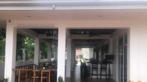 A covered outdoor area with a dining table and chairs, a small kitchen area with a counter and bar stools, and a potted plant. - Tequila Cove (Panglao)