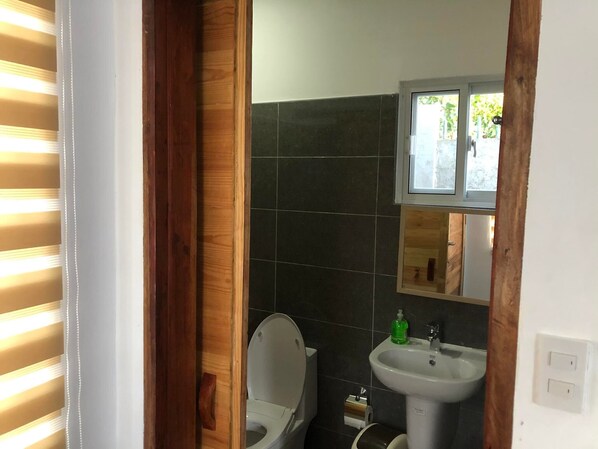 A bathroom with a toilet, sink, and mirror. - Tequila Cove (Panglao)