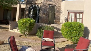 Edificio de piedra con un pozo de fuego y sillas rojas al frente.