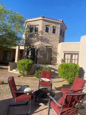 A stone building with a fire pit and red chairs in the foreground.
