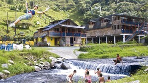 Een rustieke lodge met een houten gevel, een kleine waterval en een zwembad.
