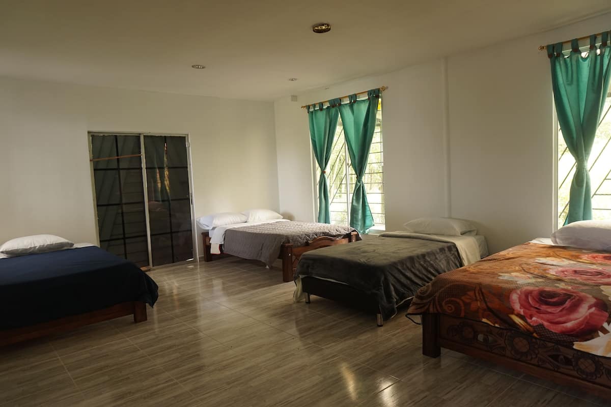 Une chambre avec trois lits, une armoire et une fenêtre avec des rideaux.