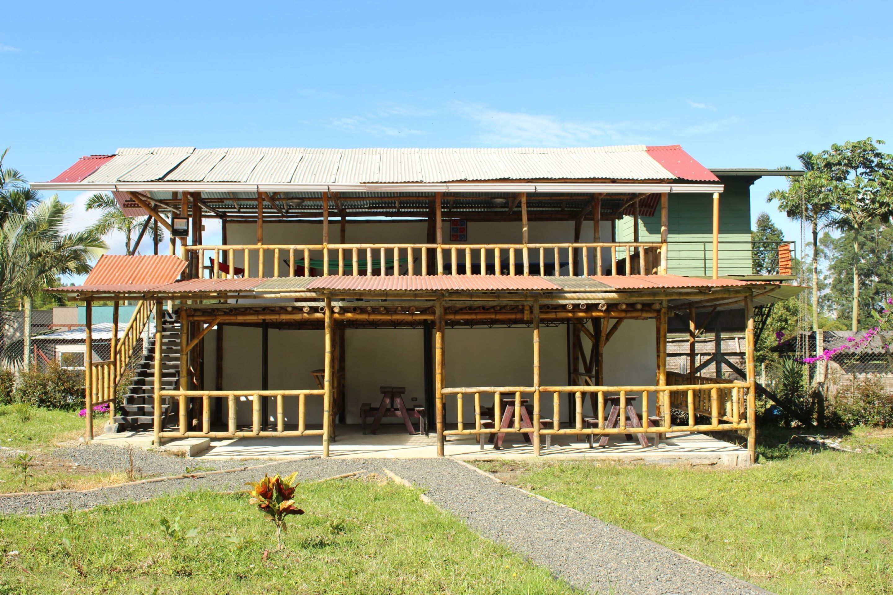 A two-story building with a balcony, a staircase, and a covered outdoor area.
