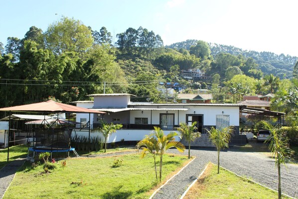 A two-story house with a covered patio, surrounded by a well-maintained lawn and small palm trees. - VILLA NATALIA (Santa Rosa de Cabal)