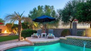 A poolside area with lounge chairs, a table, and an umbrella. - Resort-Style Oasis with Private Pool (Goodyear)