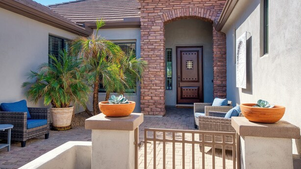 A patio area with outdoor furniture, potted plants, and a brick entrance. - Resort-Style Oasis with Private Pool (Goodyear)