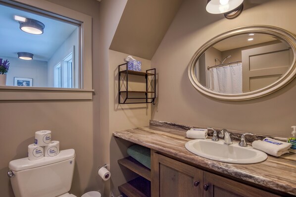 Un bagno con il water, un lavandino, uno specchio e uno scaffale con articoli da toilette.