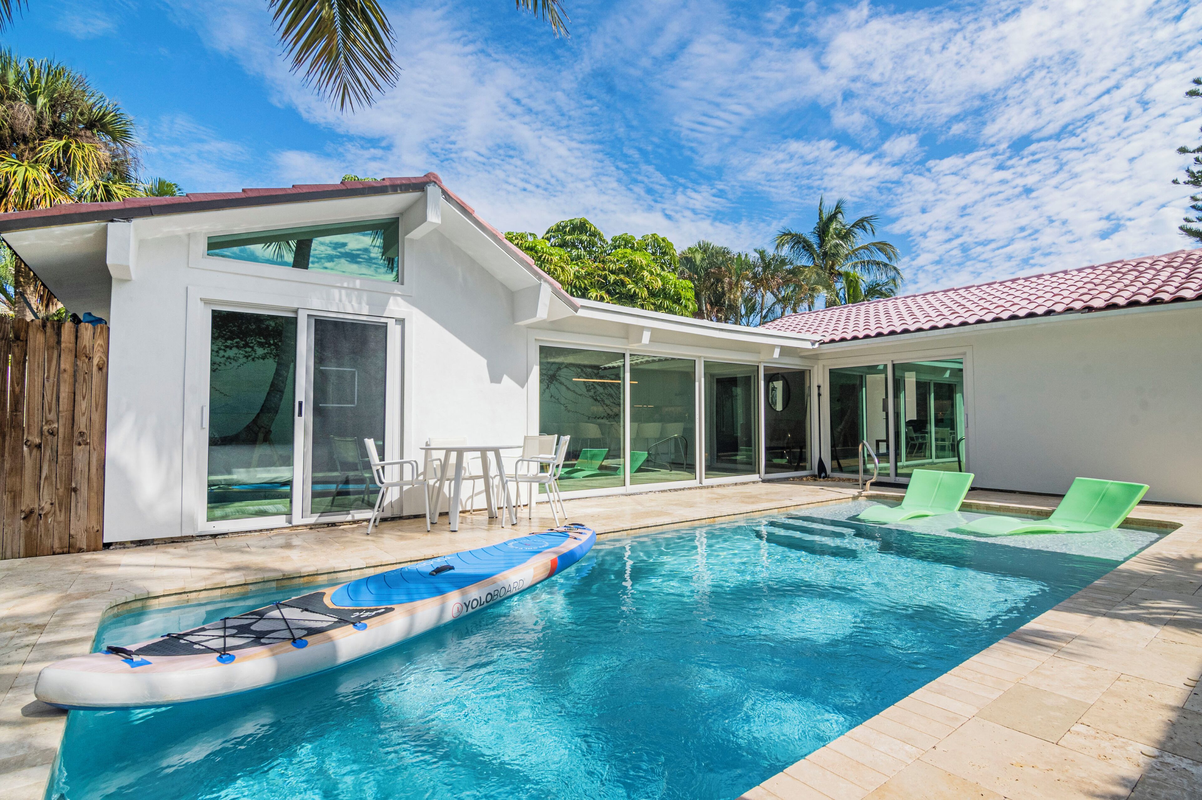 A modern house with a swimming pool, sliding glass doors, and outdoor furniture.