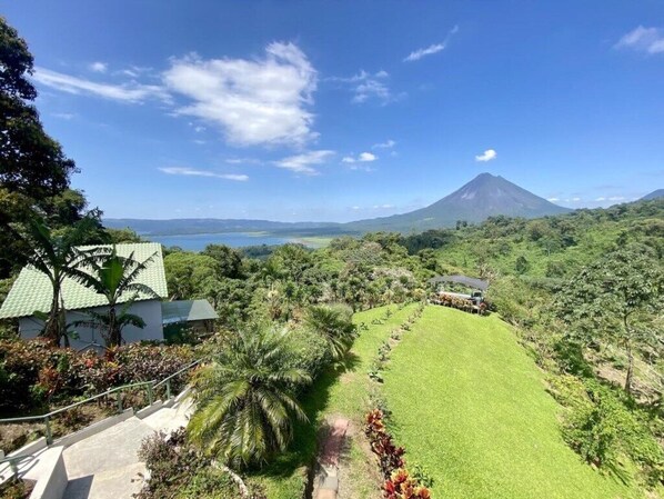 A lush landscape with a mountain in the background, a well-maintained lawn, and a building with a green roof.