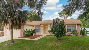 A two-story house with a front yard, a driveway, and a small tree. - Fully Fenced, Extra Large Lot, Private Pool & Spa Close to Attractions, Restaurants & Supermarkets (PG2200) (Clermont)