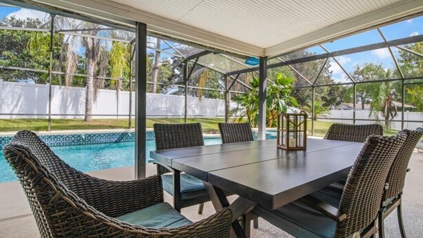 An outdoor patio with a table and chairs, a pool, and a view of trees and a fence. - Fully Fenced, Extra Large Lot, Private Pool & Spa Close to Attractions, Restaurants & Supermarkets (PG2200) (Clermont)