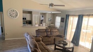 A living room with a sectional sofa, a coffee table, and a ceiling fan. - Fully Fenced, Extra Large Lot, Private Pool & Spa Close to Attractions, Restaurants & Supermarkets (PG2200) (Clermont)
