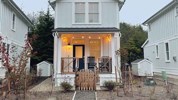 A two-story house with a porch, a mailbox, and a small garden area. - Cozy Cottage in Seabrook w/ Private Hot Tub (Pacific Beach)