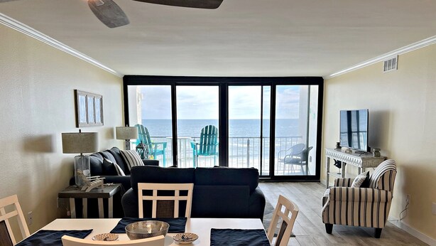 A living room with a dining area, a TV, and a view of the ocean. - The fish are biting!!🎣🌞 There is something for everyone! (Orange Beach)