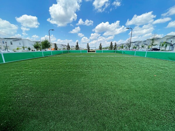 A large, open green field with a clear sky and clouds.
