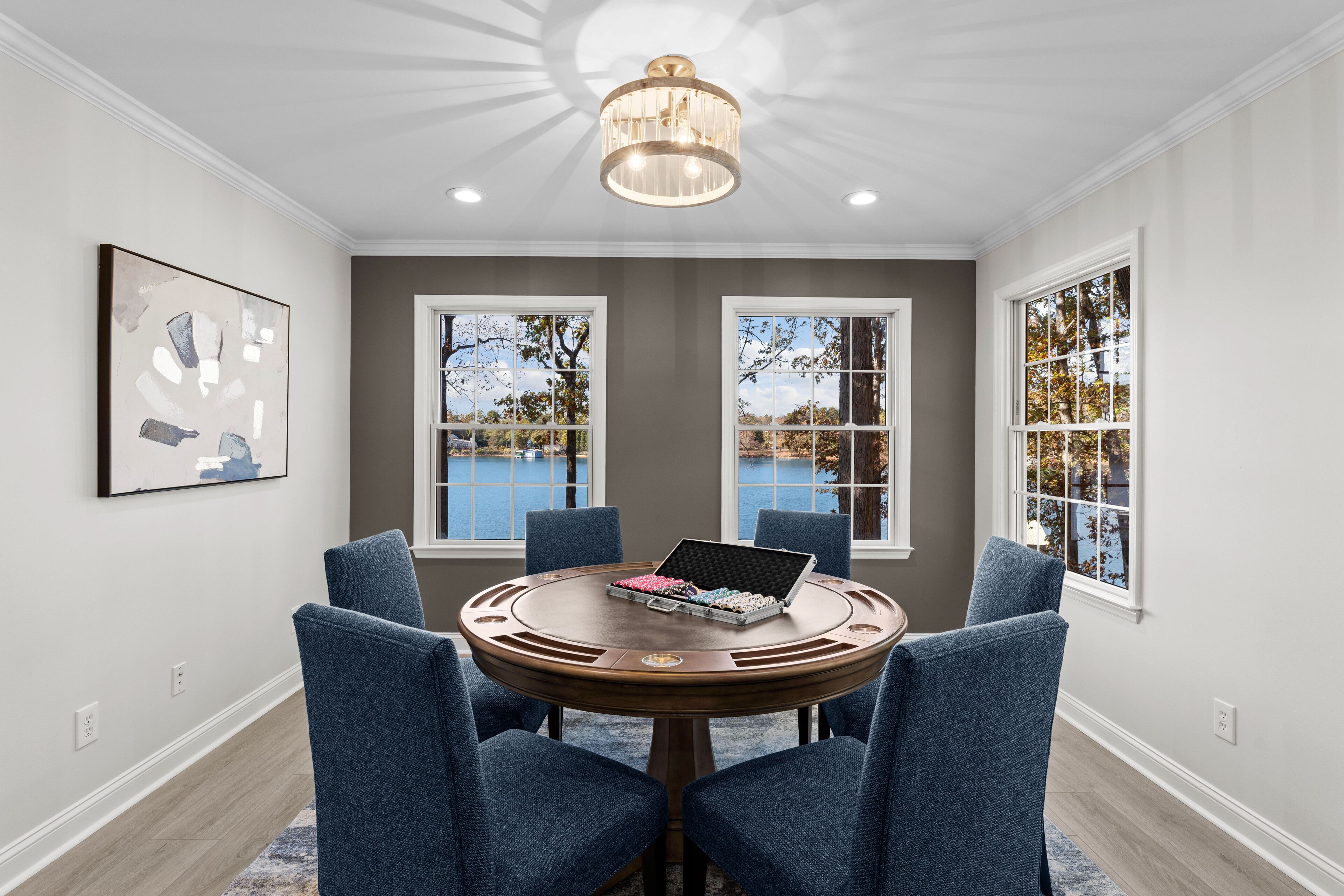 A dining area with a round table, four blue chairs, and a laptop.