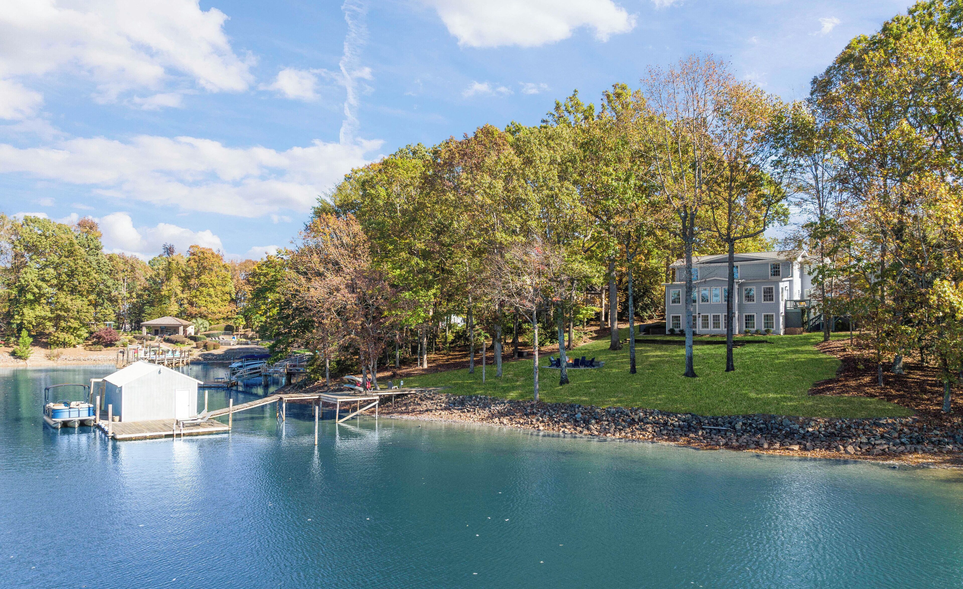A lakeside property with a dock, a large house, and surrounding trees.