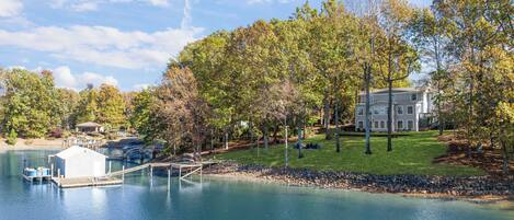A lakeside property with a dock, a large house, and surrounding trees.