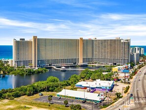 A large hotel with multiple floors, a waterfront view, and a parking lot.