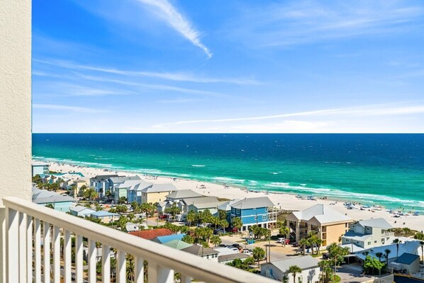 A coastal view with a beach, ocean, and residential buildings.