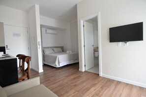 A bedroom with a bed, a desk, and a TV. - Vila do Centro Apart Hotel (Bombinhas)
