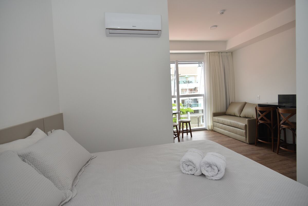 A hotel room with a bed, a desk, a chair, and a balcony with a view.