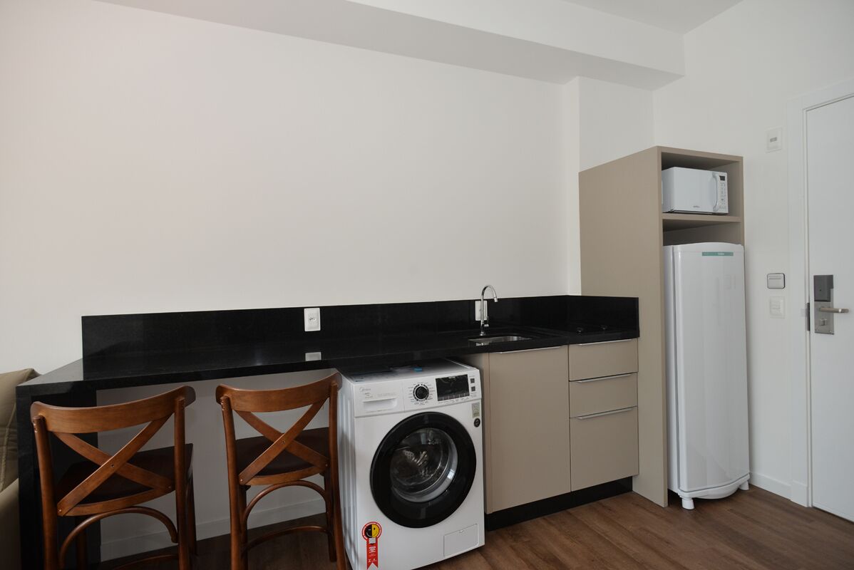 A compact kitchen with a washing machine, a microwave, and a refrigerator.