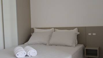 A neatly made bed with two pillows and two rolled towels.