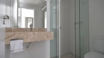 A modern bathroom with a glass shower enclosure, a marble sink, and a white toilet.