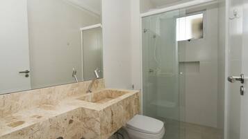 A bathroom with a marble sink, a toilet, and a glass-enclosed shower.