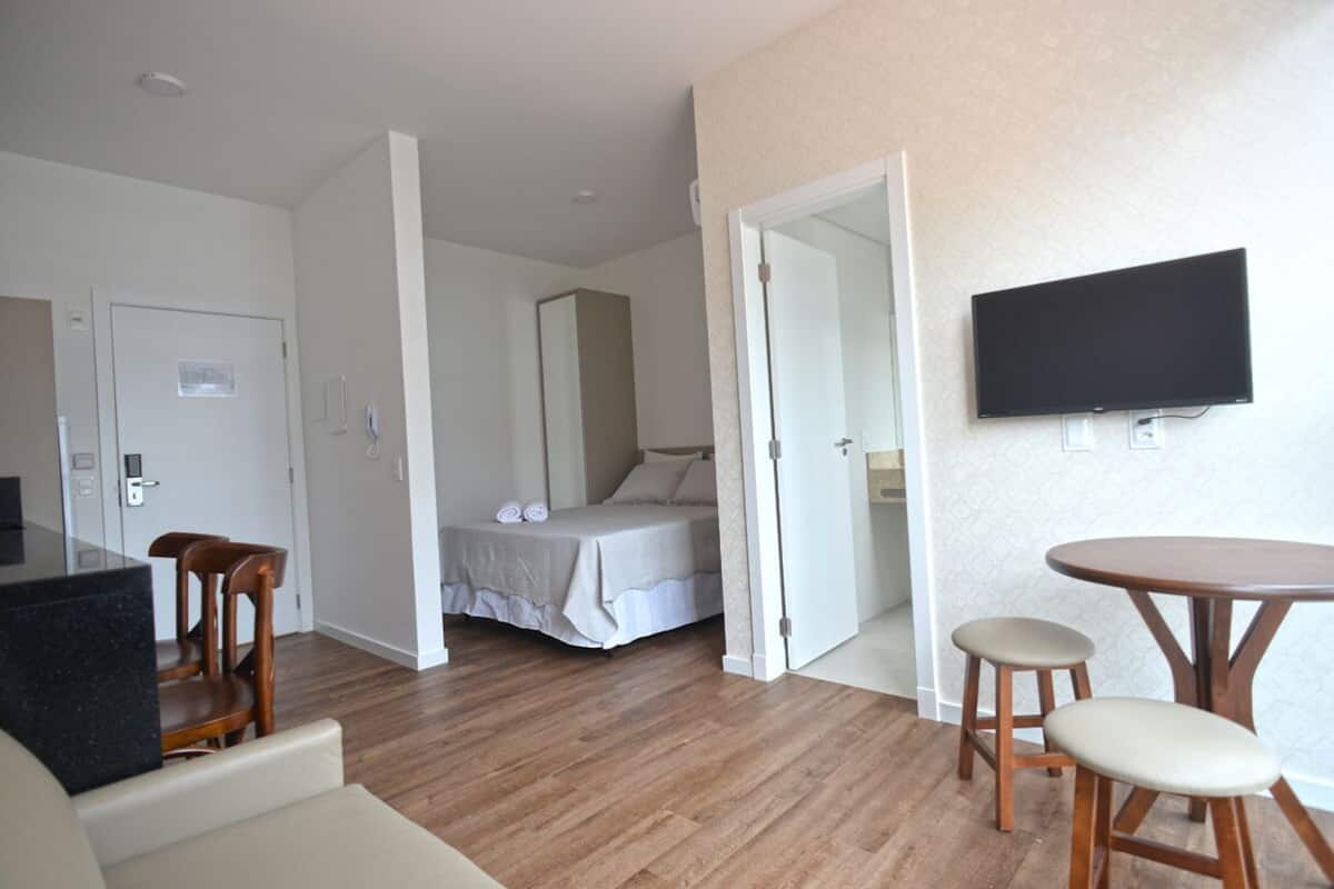 Een hotelkamer met een bed, een aan de muur bevestigde televisie, een eettafel en een stoel.