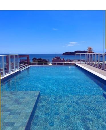 Una piscina al aire libre, sombrillas, sillones reclinables de piscina