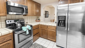 A kitchen with wooden cabinets, a stainless steel microwave, a stove, and a refrigerator. - Snow Summit Getaway - 2-bedroom in Big Bear Lake, Walk to Slopes, Cable TV, Deck, BBQ, Views (Big Bear Lake)