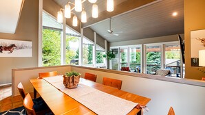 Un coin repas avec une table en bois, des chaises et une grande fenêtre donnant sur un espace verdoyant.