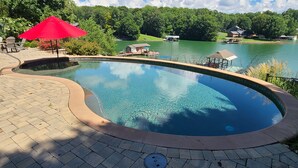 A clear swimming pool with a curved edge, surrounded by a paved deck. - Beautiful lakeside family or corporate retreat with pool, hot tub, and  more! (Huddleston)