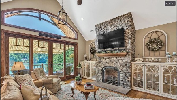 A spacious living room with a stone fireplace, comfortable seating, and a large TV. - Beautiful lakeside family or corporate retreat with pool, hot tub, and  more! (Huddleston)