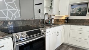Een moderne keuken met een roestvrijstalen fornuis, witte kasten en een marmeren aanrecht.
