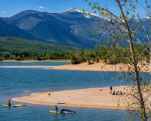 A lake with kayaks, a sandy beach, and mountains in the background.