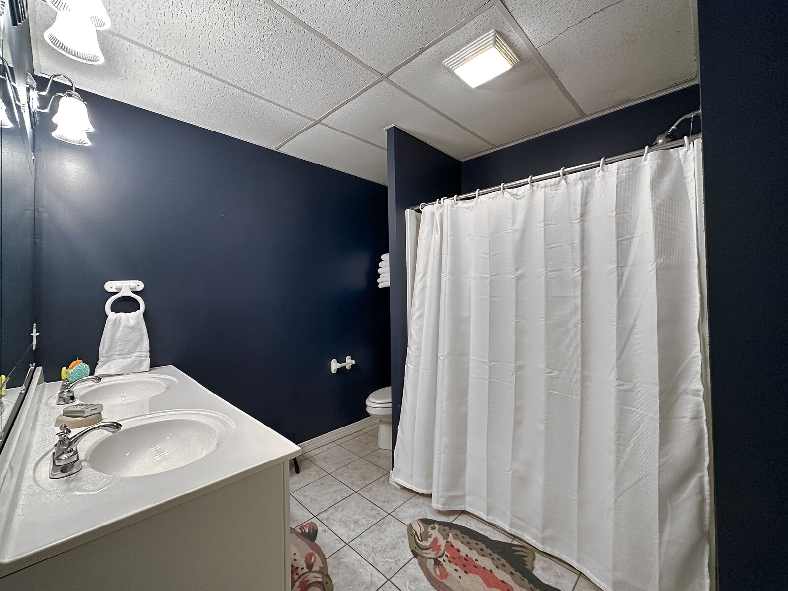 A bathroom with a white sink, a toilet, and a white shower curtain.
